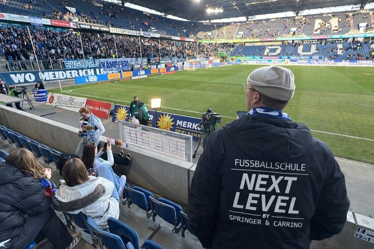 Trainer im NEXT LEVEL Pullover auf der Tribüne im Stadion